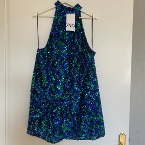 Paljettklänning - Festklänning i paljett och snygga färger, halterneck och kortare modell. Gömd dragkedja i ryggen. Passar de flesta beroende på vilken passform man vill ha. Aldrig använd, frakt ingår i priset ✨ (nypris 559 kr) 