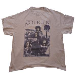 En beige t-shirt med motiv av bandet Queen. Köpt för ett år sen ungefär. Inga tydliga defekter. Budgivning sker i kommentarsfältet. Kan frakta. BUDGIVNINGEN AVSLUTAS 23:00