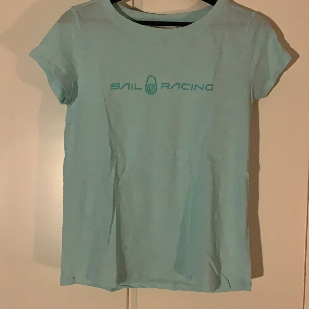 En helt ny turkos t-shirt från Sail racing med en liten logga på ryggen. Den är tvättad en gång då den åkte med på en resa men ej användes, därav är ej lappen kvar.. T-shirts.