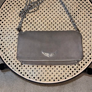 Grå zadig voltaire väska - Säljer min gråa zadig voltaire väska som är 2,5 år gammal men i väldigt fint skick. Har en liten grå fläck på baksidan därav priset