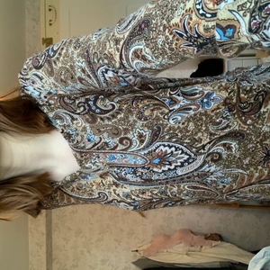 Paisley-mönstrad topp - Paisleymönstrad topp i 100% viskos. Den är riktigt mjuk och len samt har ballongärmar. Ganska stor urringning med krage. Perfekt att ha med t.ex. jeans när det är varmt väder🦋