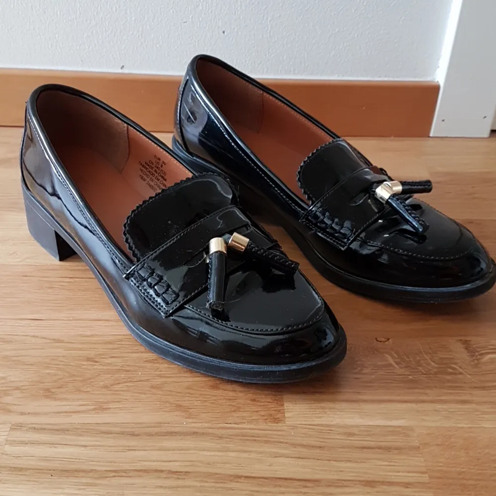 Snygga lackade loafers från H&M i storlek 39 med små guldtaljer framtill. Använda men i fint skick, sånär som på några skavmärken som uppstått när skorna har gruggats mot varandra. Finns att hämta i Göteborg eller skickas mot betalning 😊. Skor.