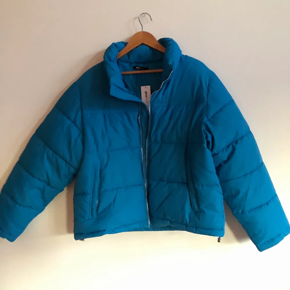 Helt ny oanvänd puffer jacket. Jackan är i storleken XL men passar även mig (första bilden) som vanligtvis bär S eller M, så funkar till alla blir bara mer eller mindre oversized. Finns 2 fickor med dragkedja, ingen luva och silverdetaljer. Har även samma fina blåa färg på insidan och går att spänna åt i midjan. Jackor.