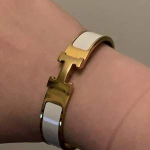 Hermes Bracelet i guld og hvid. Np 4500 dkk. Den er i god stand og ingen ridser. armbåndet er målt til 18 cm rundt om håndleddet og 12 mm i bredte. 