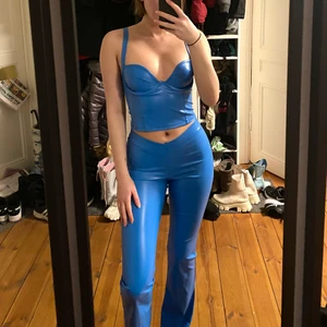 Blått fest set - Ett jättefint set med ett par blåa byxor och ett korsettliknande linne med inbyggda byglar i konstläder/latex. Stretchiga och bekväma. Perfekt för en utekväll. Använda endast 1 gång på halloween och därav nästintill nya. Säljer då byxorna tyvärr är på snudden för korta för mig (är 173cm). Skriv gärna om ni har frågor😊