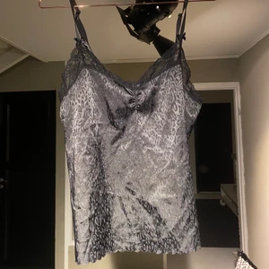 Spetslinne - Svart spetslinne med leopardmönster i glänsande tyg. Väldigt lent och har juserbara band. 