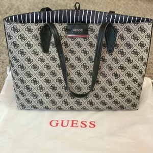 Guess väska - Guess väska med en tillhörande mindre väska som ryms i den stora väskan. Med tillhörande dustbag. Mått höjd 27,5 x bredd 40cm, lilla väskan höjd 21 x bredd 32cm. I nyskick, använd fåtal ggr.