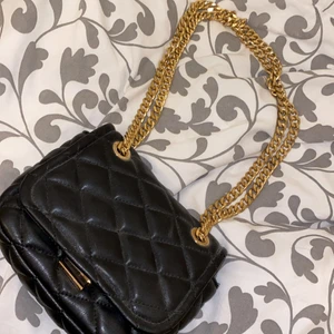 Väska svart  - En svart vanlig väska med guld kedja som du kan välja om du vill ha lång eller om du vill ha den under armen, den är i helt nytt skick, använt 1 gång och inte kommer mer till använding efter det. 