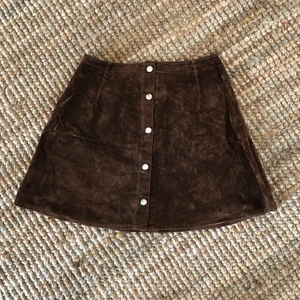 Brun kjol vintage, cirka storlek 34  - Brun kjol vintage, lite mockaliknande tyg. Tryckknappar framtill. Cirka storlek 34 