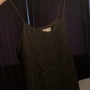 Svart spets linne stl s/m - Enkelt svart linne men dubbelt tyg fram, yttersta med blom inspirerade konturer. Baksidan har fejkknappar. Nyskick, använder inte och även för liten för mig. Det står L som storlek på lappen men liten i stl, sitter som en S/M