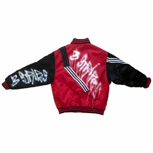 röd graffitti varsityjacka - har lagt denna på mitt andra Plickkonto också ifall den syns 2 gånger. det är en varsityjacka iallafall som jag gjort om till adidas lol,, lagt adidas stripes och vit textilspray. fråga för fler mått och bilder!!!