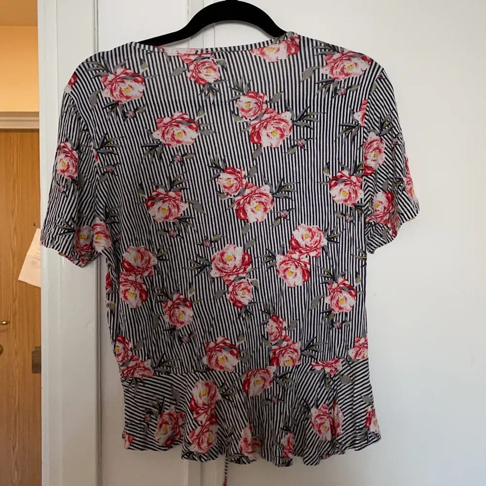 En blommig t-shirt med dragsko på framsidan. T-shirts.