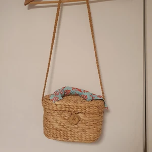 Flätad korgväska - En jättesöt flätad korgväska med tillhörande scarf. Scarfen går att ta av om man inte vill ha den på väskan. Väskan är I princip oanvänd och rymmer mer än man tror och passar jättebra till sommaren. Väskan är enkel att öppna och att stänga.🌺