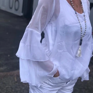 Blus/topp med volang  - Vit blus med volang. Material 100 % polyester. Storlek s/m eller L/xl . Kan hämtas i butik eller fraktas 