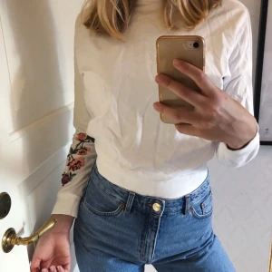 Vit tröja - Vit tröja med låg turtleneck och broderade blommor på ärmen. passar storlek XS, frakt 55kr🤍