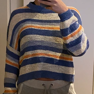 Randig stickad tröja - Stickad tröja med ränder i färgerna ljusblå, mellanblå, korall och vit. Storlek S och knappt använd. Köparen står för frakt.