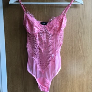 Rosa spets body - Fin body i ljusrosa färg i spets. Justerbara axelband, knäpps i med 2 knappar nedtill. Endast provad, fint skick💗