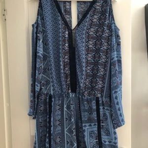 Playsuit - Blåmönstrad Playsuit från Gina Tricot i storlek 40, men passar även storlek 38. Axel-lös då man ser axeln och början av armen, även nedanför urringningen och ryggen. Aldrig använd. Nypris 299kr. Sitter väldigt fint på 