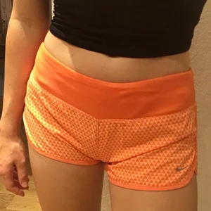 Nike träningsshorts - Säljer mina orangea Nike träningsshorts som har blivit för små. Jättefina och inte alls använt mycket. Har ficka bak där man får plats med nycklar. Jättesköna att springa eller träna i men går minst lika bra att ha hemma eller på stan!