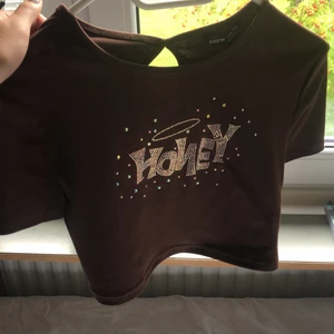Honey topp - Brun topp med glitter där det står honey på, jätte snygg o gullig. ALDRIG ANVÄND. Passar xs-l då den är stretchig 