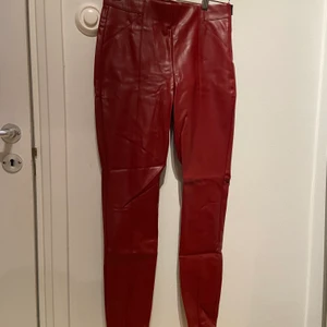 Röd fejklädder byxor - Röda fejk skinnbyxor från Zara i storlek M. Finns dragkedja på sidan och nere vid fötterna. Väldigt sköna och sitter snyggt, dock har de blivit för små så därav säljer jag de. Använda 2 gånger. 
