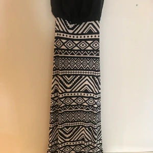 Svart/vit långklänning stl M - Svart/vit lång bandeuklänning, använd en gång, sprunn nertill, stretchtyg 