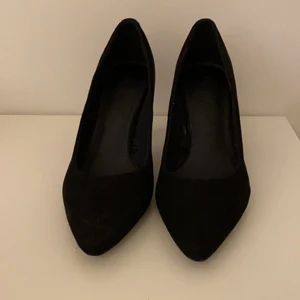 Svarta klackskor från Monki - Svarta lågklackade kittenheels i mocka immitation från Monki. I mycket bra skick då de aldrig burits utomhus. Spetsig tå. Klackhöjd 3 cm. 