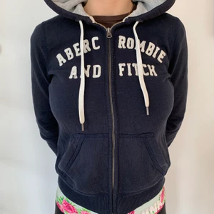 Hoodie från Abercrombie & Fitch - Mörkblå superskön och mjuk Hoodie helt utan skavanker. Grått tyg i luvan. 