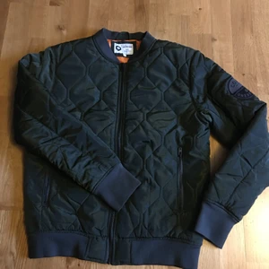 Bomberjacka  - Helfräck Bomberjacka från Jack & Jones.             Militärgrön med orange foder, strl M.                             Jätte fint skick, som ny.                                                   Frakt tillkommer 