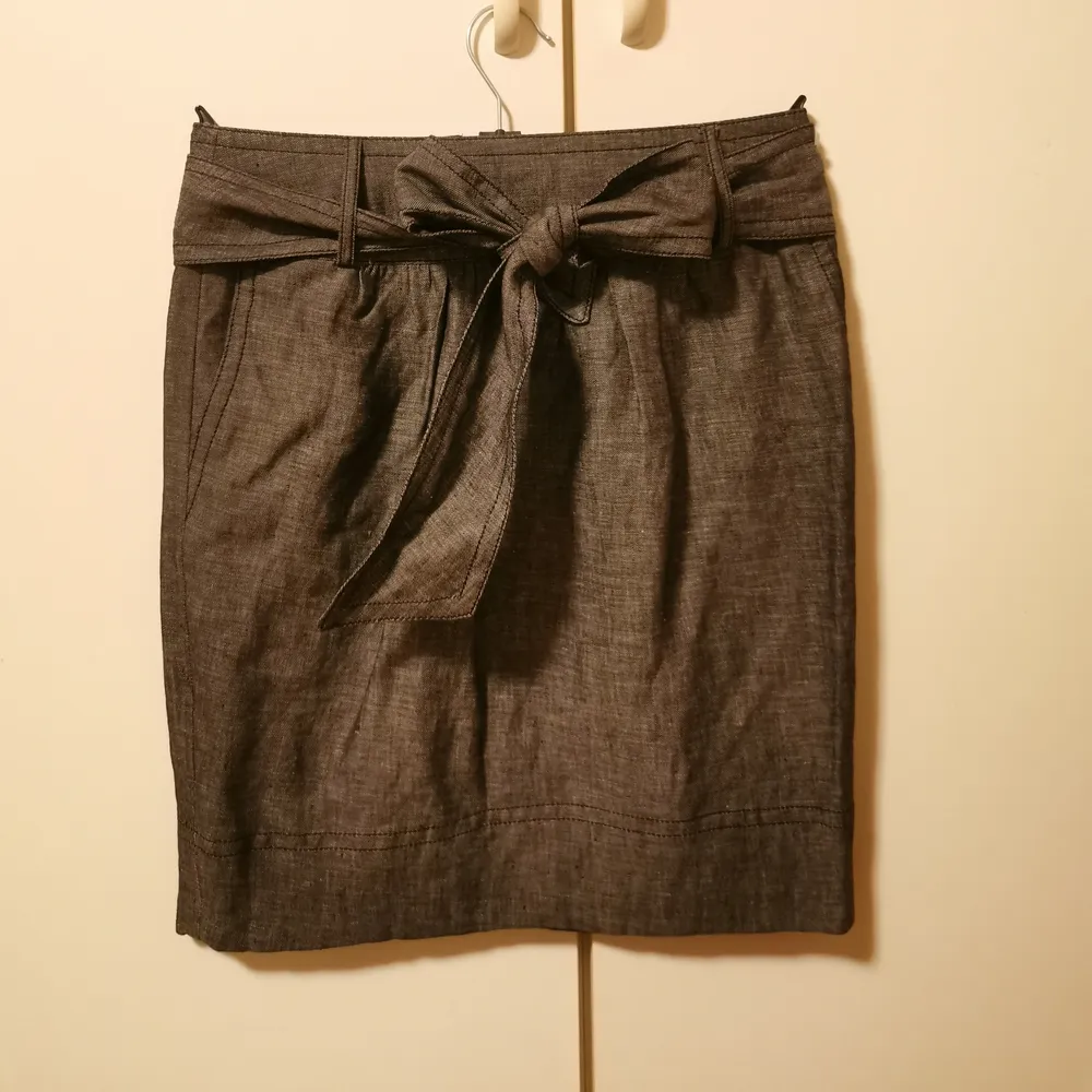 Jättefin mörkgrå kjol i typ linne-aktigt material. Storlek UK6/US2/EU34Avtagbart knytband i midjan, dold dragkedja bak. En liten 