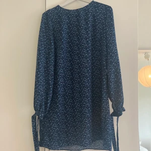 H&M blåblommig kortklänning - Blåblommig klänning från H&M, väldigt skön till sommaren! Knappt använd så fint skick. Strl 42 men pga den lösa passformen passar den både större och mindre storlekar!