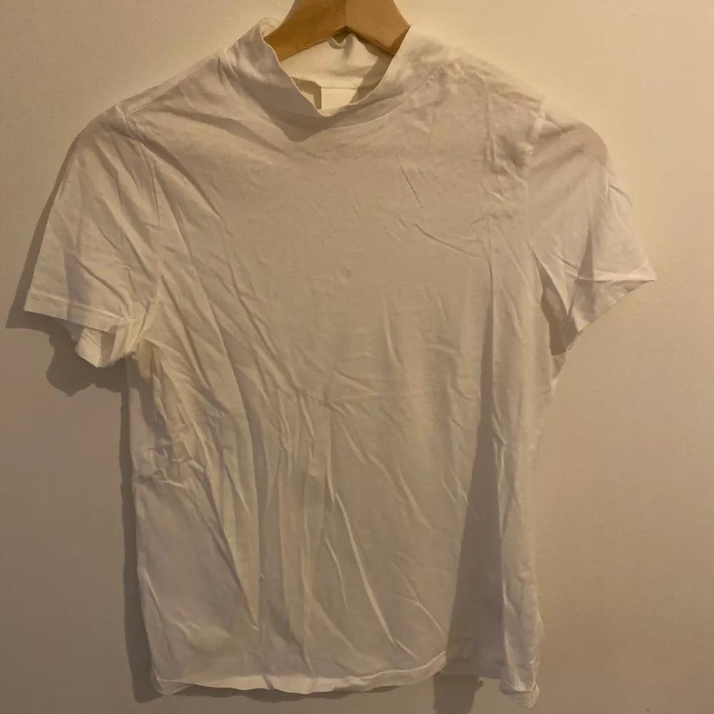 Säljer en basic vit T-shirt från hm med hög nacke, använd ett par gånger men i fint skick!🤍. T-shirts.