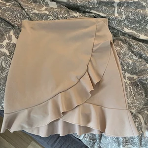 Kjol - Säljer denna kjol från Nelly, volanger i beige rosa färg, storlek S, bra skick säljer för 80kr + frakt☺️