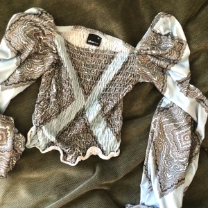 Mönstrad topp - En mönstrad topp från gina tricot som är tight över mage/rygg med lösa ärmar. Är mellan crop top och vanlig längd. 