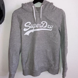 Superdry hoodie  - Grå superdry hoodie storlek M med superdry tryck på framsidan. Hoodien har även japanska bokstäver på ena ärmen. Skulle säga att den är lite liten i storleken. Använd men i bra skick.