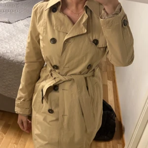 Beige trenchcoat - En oanvänd trenchcoat i storlek 34. 