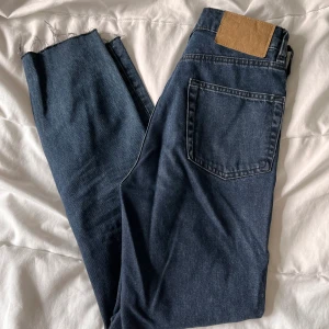 Blå momjeans strl 32 - Momjeans strl 32 från H&M. Går till ankeln på mig som är 170cm. Mörkblå. Säljes pga för små för mig! 