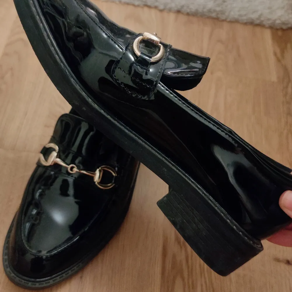 Svarta glansiga loafers med guldig detalj på framsidan och höjden på klacken är 3 cm. Använd endast några fåtal gånger!. Skor.