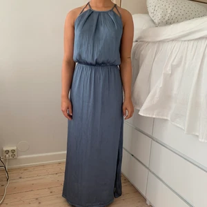 Satinklänning i stl 32 - Gråblå silkesklänning från H&M i stl 32. Guldig knäppning i nacken, Resåren i midjan är stretchig. Använd 1 gång. Inga fläckar/slitage. Köpt för 600kr.