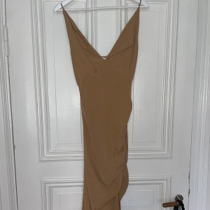 Brun klänning  - Använd en gång. faller väldigt fint och fina detaljer vid benen samt framtill 