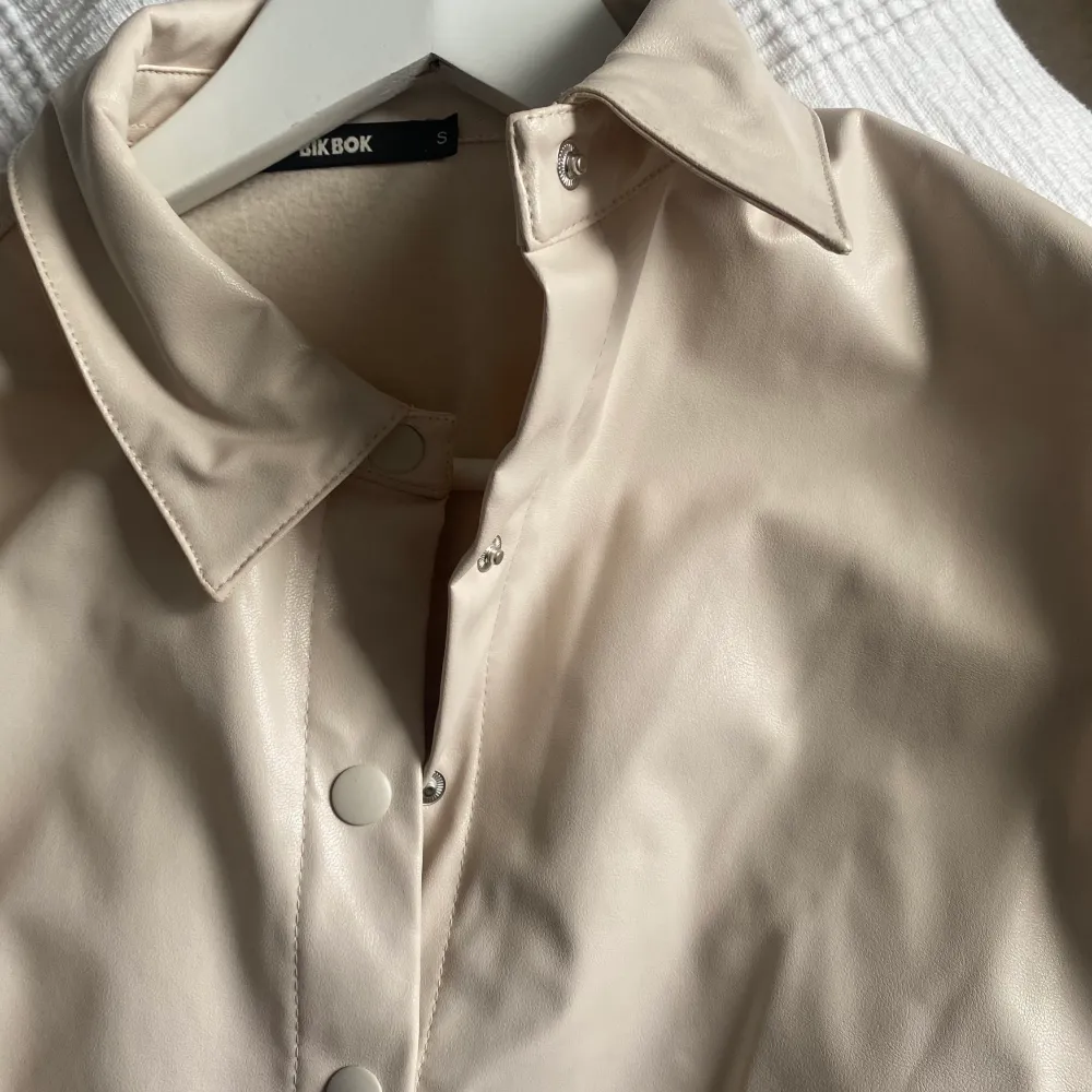 tunnare jacka. knappar framtill & längst ner på ärmarna. ljus beige färg.. Takit.