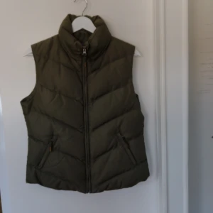 Grön väst  - Snygg grön väst i strl M. Från ZOUL. Väldigt bra skick använd nån gång. Innehåller 70% dun och 30% fjädrar.