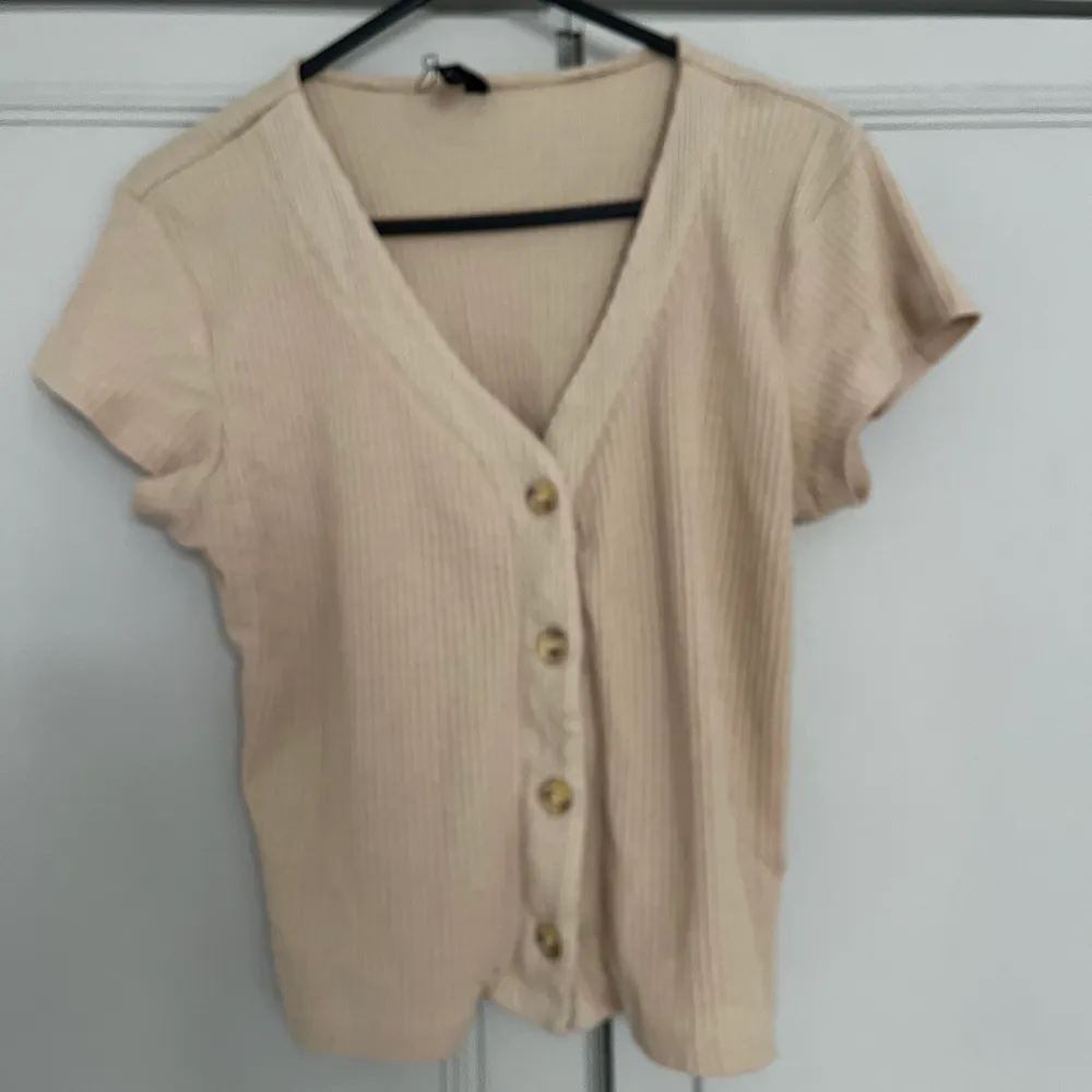 Beige button-up crop top for those hot summer nights. Size L but fits a size M/L. Toppar.