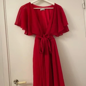 Röd klänning - Röd klänning från bubbleroom med wrap klänning liknande modell med knytskärp i midjan. V ringning. Något ihopsydd i mitten för att inte vara fullt så v ringad, går lätt att sprätta upp om man vill det. Strl 42 eller L. 