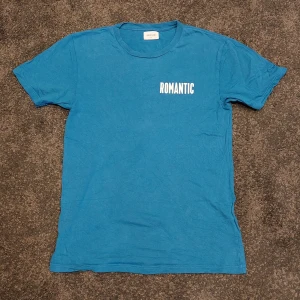 Romantic WOOD WOOD t-shirt - Blå WOOD WOOD tröja i bra skick. Använd ett få tal gånger. Motiv "ROMANTIC"