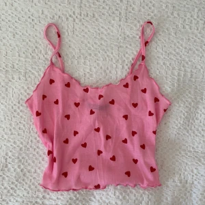 Linne med hjärtan  - Säljer detta jättesöta rosa linne. Det har röda hjärtan och lite volanger och är ganska kort. I superfint skick ❣️❣️