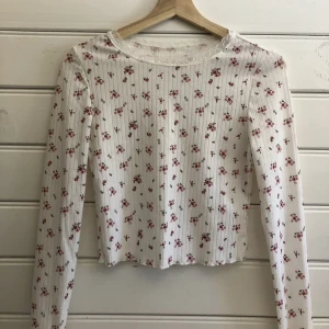 Blommig topp - En rosa blommig topp med vit spetsdetalj i kragen. Köpt här på plick men har själv aldrig använt den. 