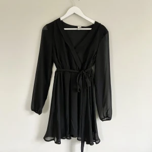 Nelly klänning - En helt oanvänd svart långärmad miniklänning från NLY trend. Den har ett band runt midjan som går att knyta. Fin till fest eller middag!  Storlek: 34 Material: 100% polyester Skick: Oanvänd