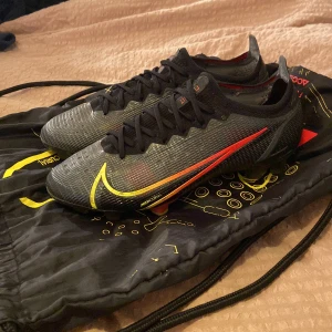 Nike vapor 14 elite FG - Säljer nu mina snygga Nike vapor 14 elite FG i storlek 39. Skorna är i 8.5/10 skick. Nypris är 2799. Det är gått hål i hälen inne i skon men där sitter en laglapp. Påse medföljer men ej box. Skriv för fler bilder el frågor.  