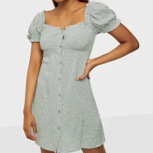 Klänning - Grön klänning med blommor ifrån Nelly. Aldrig andvänd. Storlek 32 men passar även 34. 